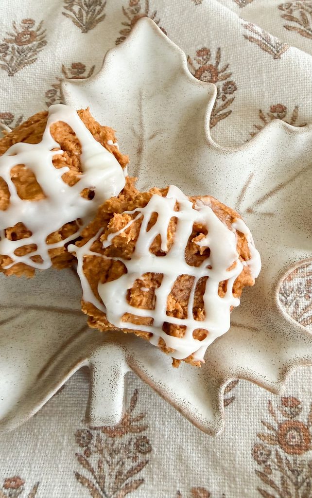 Close up of pumpkin spice cookies with cream cheese drizzle on small ceramic maple leaf dishes