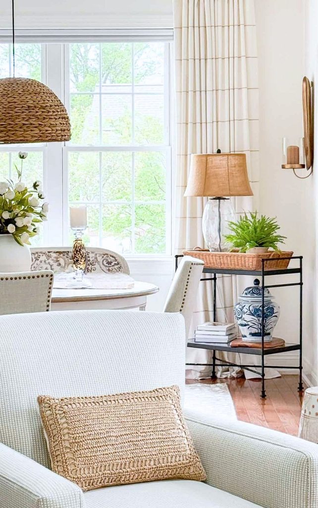 Dining room with woven pendant light, iron bar cart styled with a blue and white ginger jar, rattan tray, and burlap lamp