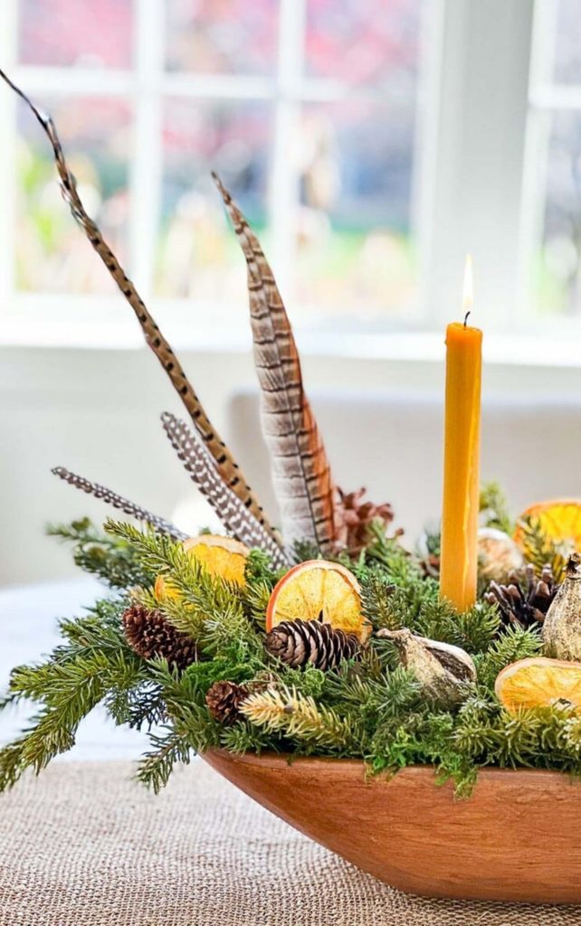 dough bowl with greens, pinecones, orange slices and pheasant feathers