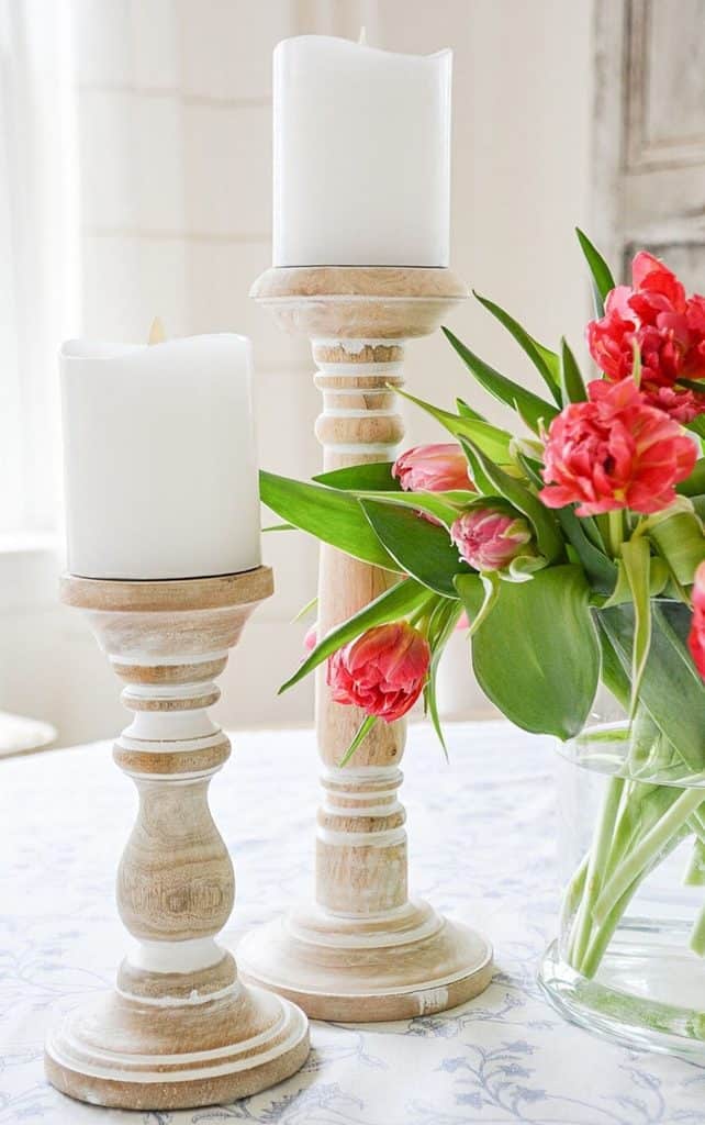 chunky wood candle pillars next to a vase of pink parrot tulips